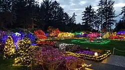 View west across the garden from the pavilion showing the southern half. Walkways and plants are decorated with holiday lights.