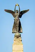 Winged figure holding a golden crown at the top of the obelisk