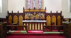 Panoramic photograph of the hand carved and painted cedar woodwork in the St John's chancel, with red carpet