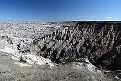 Rocky sand-color mesa table surrounded by many steep erosion gullied