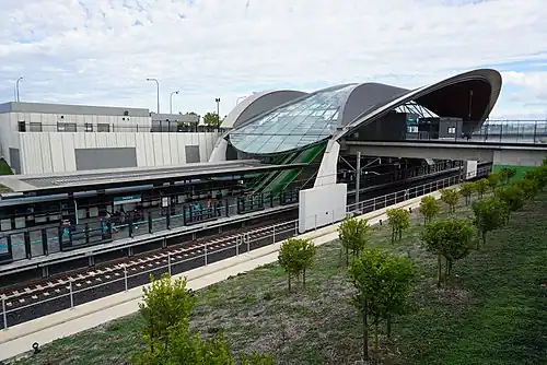 Picture of Tallawong station viewed from the outside. It consists of a curved roof covering a platform in a cutting below ground.