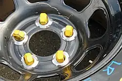 Five yellow lug nuts for use on a car with wheel studs
