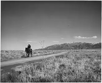 "The road to Arroyo Seco; in the distance, the Sange de Cristo Mountains, from whose melting snow comes most of the water of the area," December 1941