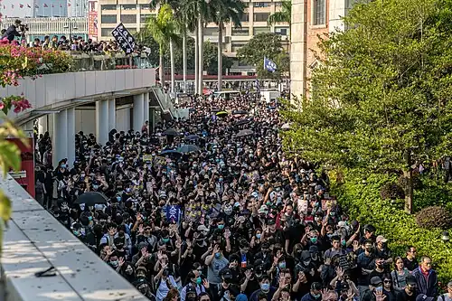Protesters raising their hands with their palms open chanting "Five Demands, Not One Less"