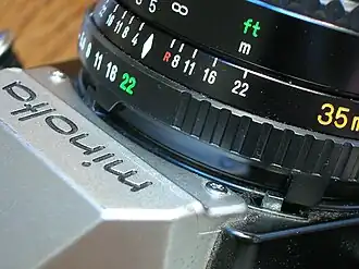 The MD tab displaces a separate tab on the camera body (colored silver, in the bottom right corner of this photograph) when the lens is set to its minimum diaphragm (f/22) for shutter-priority autoexposure.