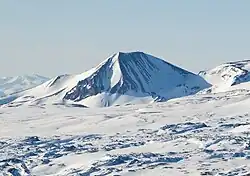 A pyramid-shaped mountain peak largely covered in snow