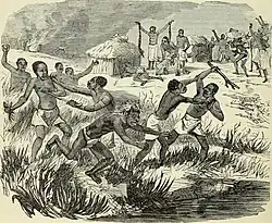 Several groups of black people are fighting in the tall grass with weapons. In the background of the image is a village with festive activities and what looks like a man practicing a ritual.