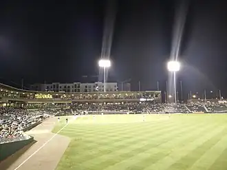 A green baseball field and its grandstand at night
