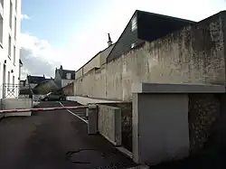 Along Rue Élise-Dreux, the wall of the Saint-Éloi bastion borders a building courtyard.