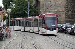 Seven-section red and white tram on a cobbled road