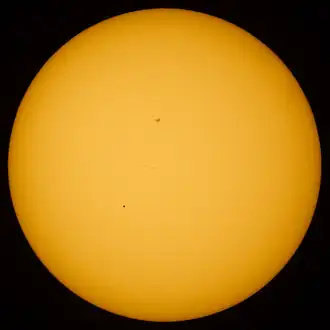 Transit of Mercury. Mercury is visible as a black dot below and to the left of center. The dark area above the center of the solar disk is a sunspot.
