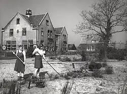 Schoolgirls at work, the school building in the background, April 1946