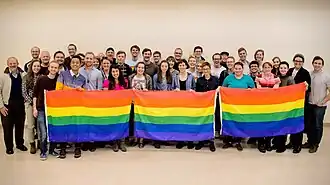 A group of BYU students holding up three rainbow flags