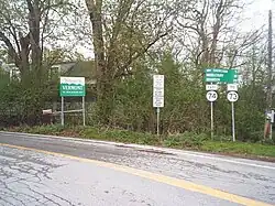 Ground-level view of a road with a series of signs visible on the right side.