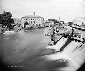 A view of an island with a river and weir in the foreground