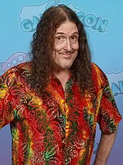 "Weird Al" Yankovic in a multi-colored shirt, against a white background