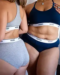 Two women wearing "Woxer" brand high-cut briefs and sport bras