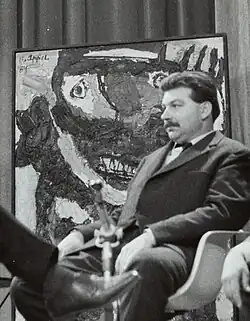 photo, 1959 of Karel Appel with his painting (1954), on the background; - quote of Karel Appel, 1958: 'I don't paint, I hit'