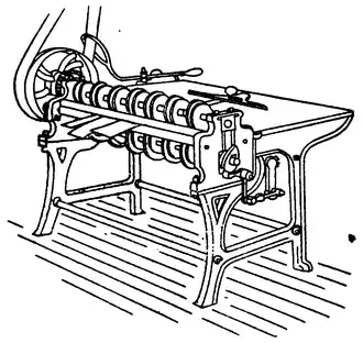 Line drawing of a table-like machine, with many wheels along the near edge, connected to a a larger, belt-powered wheel.