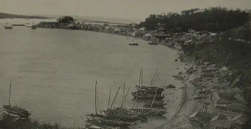 This photo shows a beach on Fusan Bay in southeast Korea. Little sail boats are anchored by the sand. No passenger or cargo ships are seen at this angle.