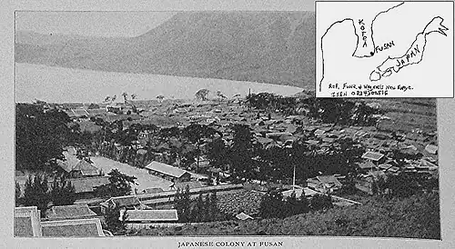 This picture is from a hill overlooking the rooftops of a neighborhood on the shore. The sea looks like a lake because on the right side of the picture the land curves up around the water to a hilly shore on the other side of the water. On the left side of the picture, however, the water reaches the left edge of the picture. In the upper right corner, a map is sketched. It shows Korea is near Japan and that Fusan is in the southeast of the Korean peninsula.