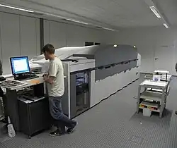 Photograph of a large, room-sized digital printer being operated.