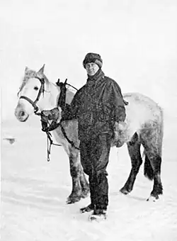 Photo of a man standing with a harnessed pony