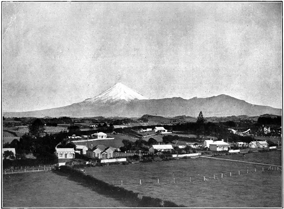 Settlement with several houses spread out along roads, with Mount Egmont (Taranaki) in the background