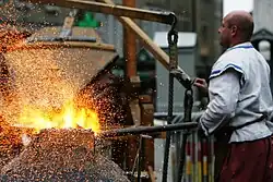 Colour photograph of a blacksmith working at a forge.