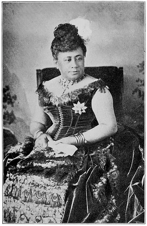 A woman seated and wearing an ornate dress