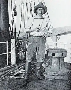 Photo of a man with a pipe standing on the deck of a wooden ship