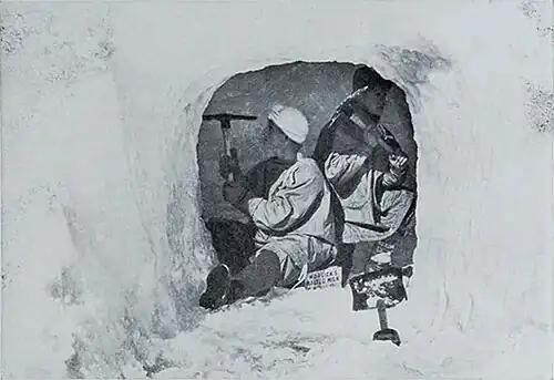 Photo of two men using picks to excavate a small ice cave