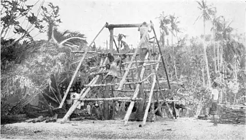 A photo of a man standing on scaffolding, building a structure