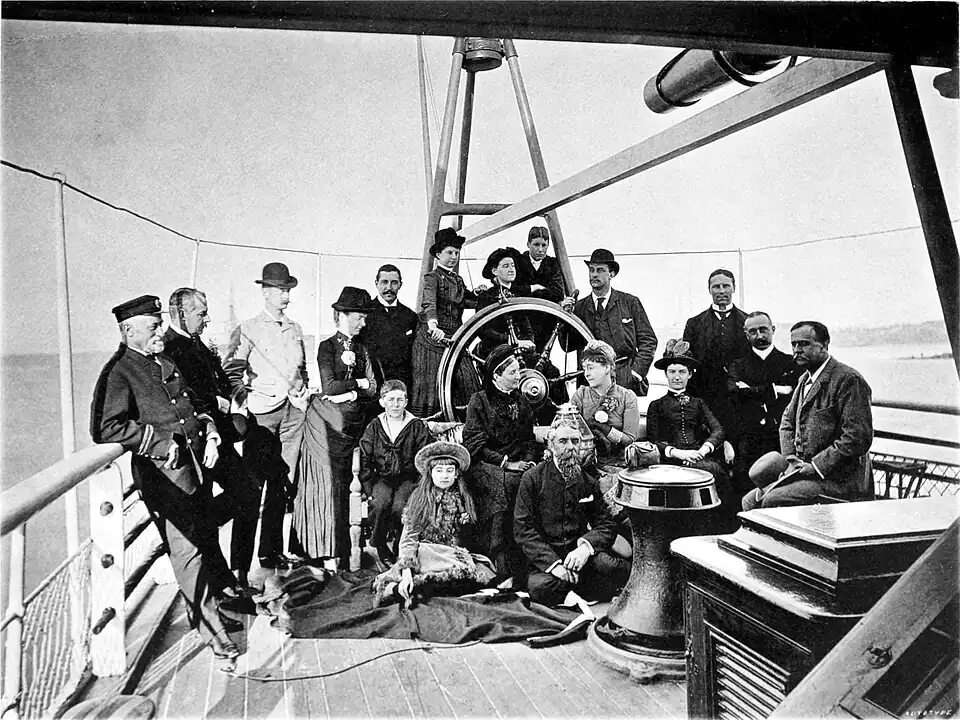 Black and white photograph of a group of men and women posing on the desk of a steamship.