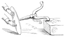 2nd of a three-part sketch showing how, rocking a small three-legged table with her hands on its top, a medium makes the table seem to climb onto an ottoman of its own accord.