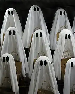 Lots of small sheets-with-eyes-style ghosts holding baskets