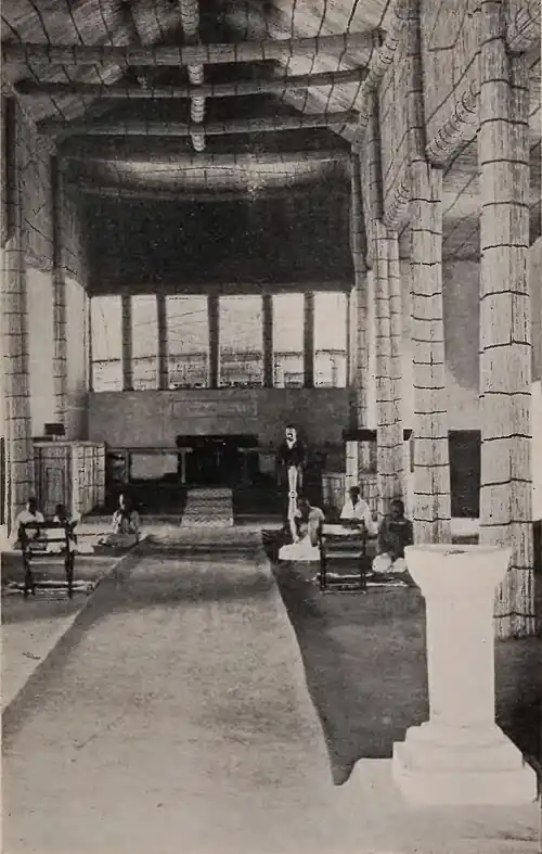 A small group, mostly seated, inside a largely empty building