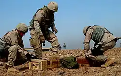 Photograph of three U.S. Air Force airmen unpacking boxes of C-4 explosive in the desert