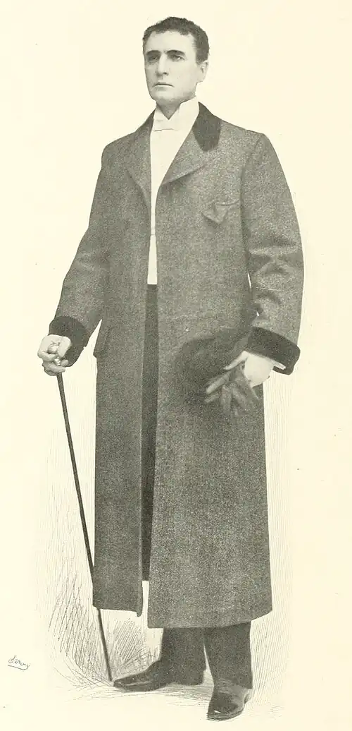 William Gillette as Sherlock Holmes, standing with a walking stick and wearing an overcoat, photographed by Sarony.