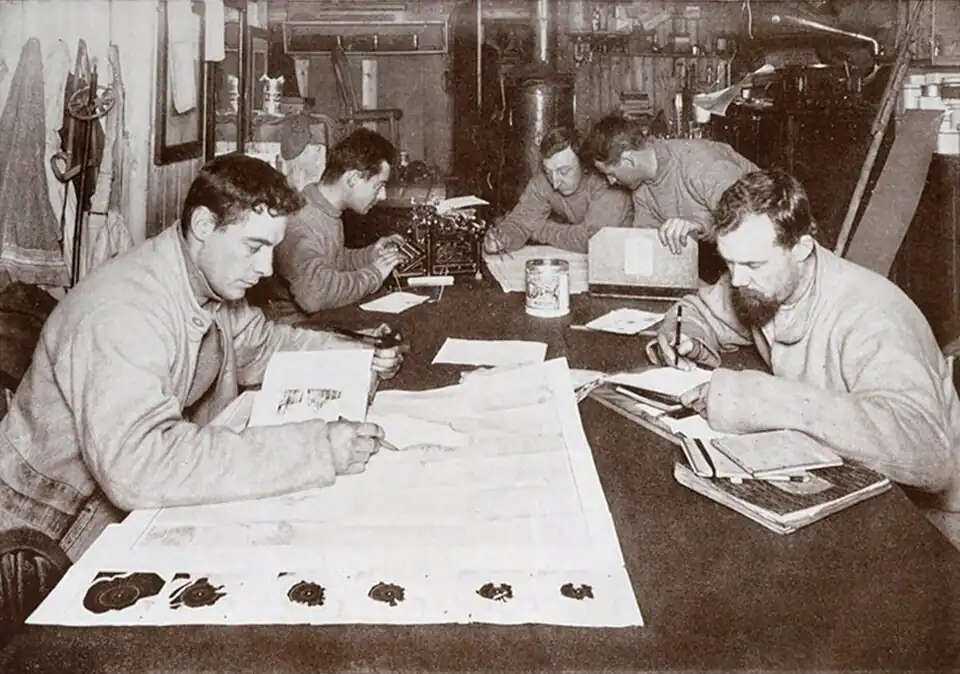 Photo of five men working independently around a large table