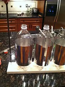 Step 8: Screwed the outer two bottles to the wood with a long rod, duct tape, and plumbers putty. Cut a metal rod ,similiar to a coat hangar, filed the end to a point (for a better spin), and used for the middle bottle.