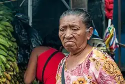Older woman with a disappointed look on her face in a busy market place.