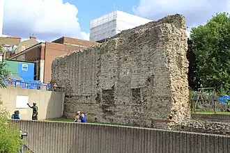 Photograph of a large section of wall.  Grey stones with lines of red tile at intervals near the base.