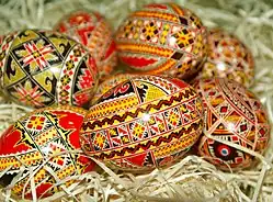 A pile of Romanian painted eggs, with black, red, and gold folk designs.