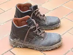 Muddy leather shoes on tile floor