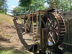 A wooden water wheel with water flowing over it.